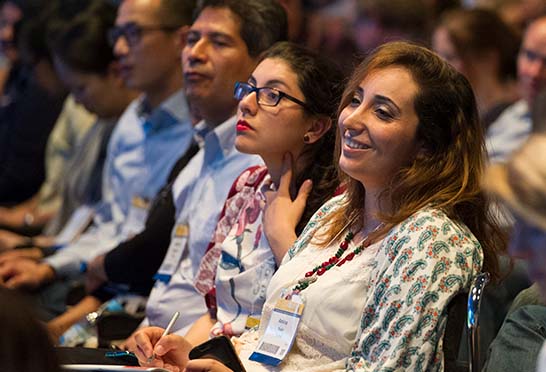 Meeting delegates smile as they watch a movement disorders presentation.