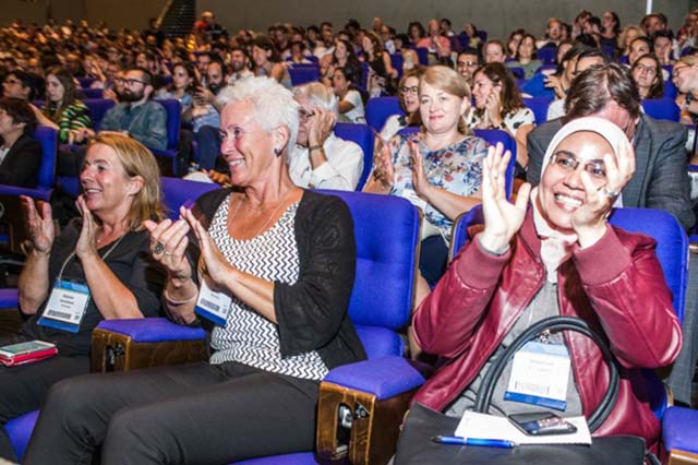 A crowd of delegates from around the globe clap at the International Congress.